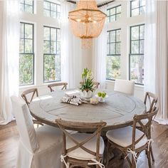 the dining room table is set with white chairs and a chandelier above it