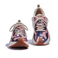 a pair of sneakers with camouflage print on the side and white soles, one in pink