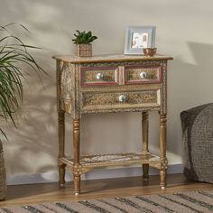 a small wooden table with two drawers and a potted plant