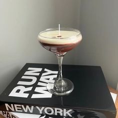 a drink in a glass sitting on top of a book