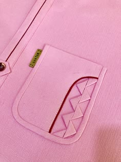 a pink shirt with a small patch on the chest and an arrow in the pocket