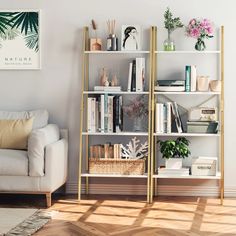 a white couch sitting next to a book shelf filled with lots of books and plants