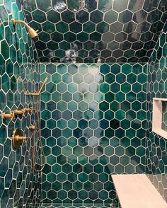 a green tiled shower with gold fixtures and hexagonal tiles on the walls, along with shelves