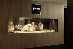 three chefs are preparing food in a kitchen window with the jones logo on it's side