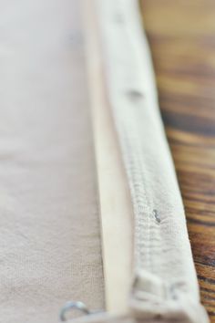 a close up view of a piece of cloth on a wooden table with a metal hook