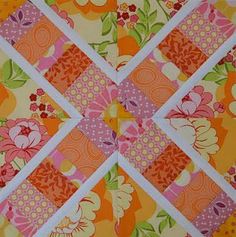 an orange and pink patchwork quilt with flowered squares on the center, which has been cut in half