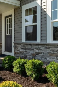 the front of a house with landscaping in front of it and bushes on the side