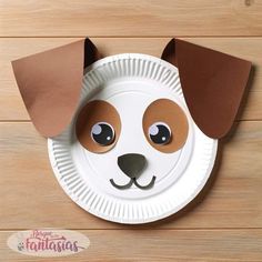 a paper plate with a dog's face cut out of it on a wooden surface