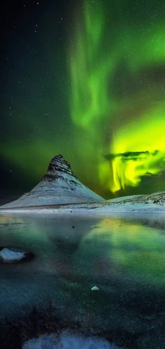 the aurora bore is shining brightly in the night sky over a frozen lake and mountain