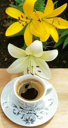 a coffee cup and saucer with yellow flowers in the background