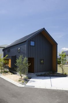 a black building with a wooden door on the side of it and trees in front of it