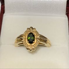 a gold ring with a green stone in it's center sits inside a white box