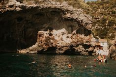 people swimming in the water near some cliffs