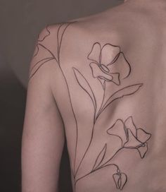 the back of a woman's upper half with flowers on her left shoulder and chest