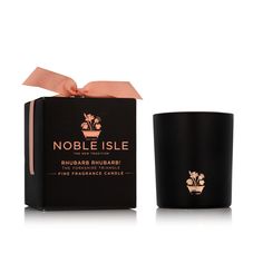 a candle with a pink ribbon around it in front of a black box that says noble isle