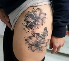 a woman's thigh with butterflies and flowers tattoo on the side of her leg