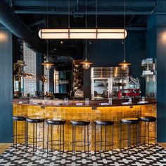 a bar with several stools and lights hanging from it's ceiling in a restaurant