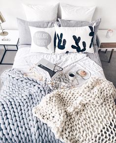 a bed topped with pillows and blankets next to a laptop on top of a table