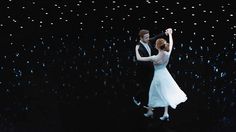 a man and woman are dancing in the dark with stars on the ceiling behind them