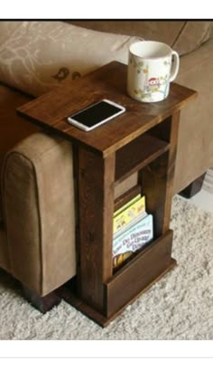 a wooden table with a book shelf underneath it and a coffee cup on the end