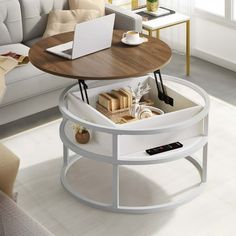 a coffee table with a laptop on it in front of a white couch and window