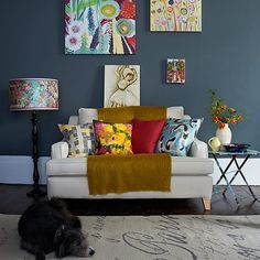 a living room filled with furniture and paintings on the wall above it's couch