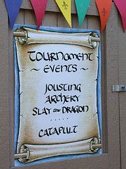 a sign on the side of a building that says, tournament events jousting archery slay the dragon catapult