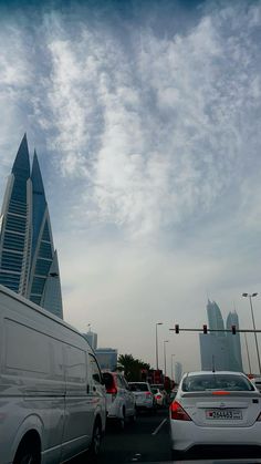 several cars are driving down the road in front of tall buildings and skyscrapers on a cloudy day