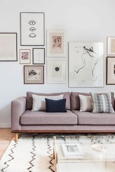 a living room filled with furniture and framed pictures on the wall above it's coffee table