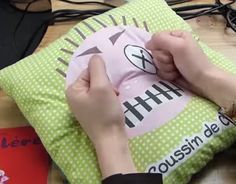 a person is sewing on a pillow that has the word hh written on it