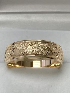 a yellow gold wedding band with an intricate design on the inside and outside of it