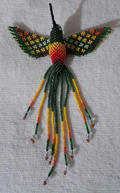 a beaded humming bird ornament hanging on a white fabric background with beads