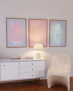 a white chair sitting next to a table with two pictures on it and a lamp