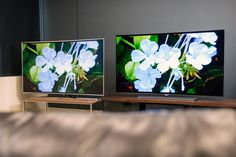 two televisions sitting on top of a table next to each other with flowers on them