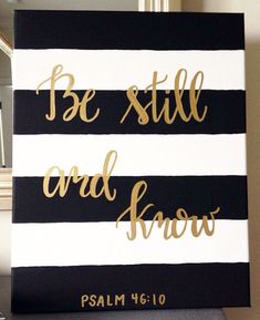 a black and white striped canvas with gold foil lettering that says be still and know