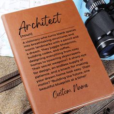 an orange leather book with the words, architecture written on it and binoculars next to it