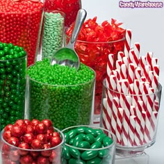 many different colored candies in glass containers with spoons and candy canes next to each other