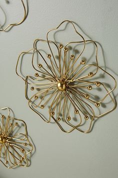 three metal wall hangings with gold balls in the shape of flowers on a white wall