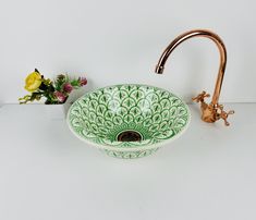 a green and white bowl sink sitting on top of a counter next to a faucet