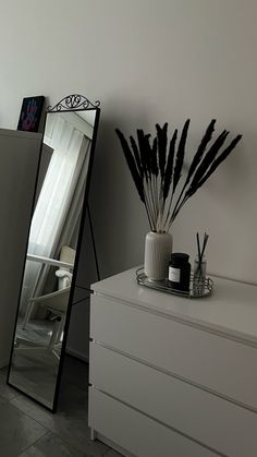 a white dresser with a mirror and vase on it