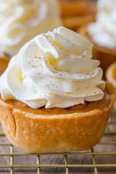 some cupcakes with white frosting on top are cooling on a wire rack