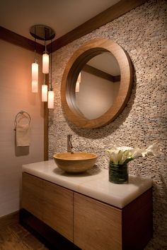 a bathroom with a round mirror above the sink and wooden cabinet below it, along with two lights on either side of the vanity