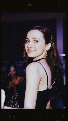 a woman in a black dress posing for a photo with her hair up and eyes closed