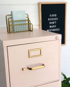 a pink file cabinet sitting next to a chalkboard with writing on it and a pen holder