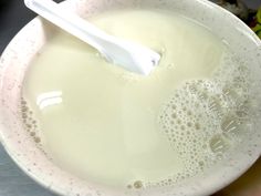 a white bowl filled with liquid and a toothbrush