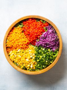 a wooden bowl filled with different colored vegetables