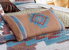 a bed with a brown and blue quilt on it's headboard next to a window