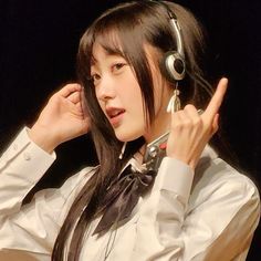 a young woman wearing headphones and holding her hand up to her ear while talking on the phone