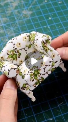 someone is holding a small object with flowers on it's sides and the bottom part has been made out of fabric