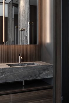 a bathroom sink sitting under a mirror next to a wooden cabinet and wall mounted faucet